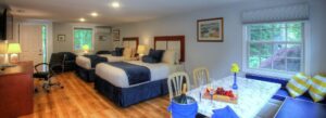 Two queen-size beds, comfortable seating, and a dining set with a fruit and cheese tray and a bottle of chilled wine paired with two wine glasses.