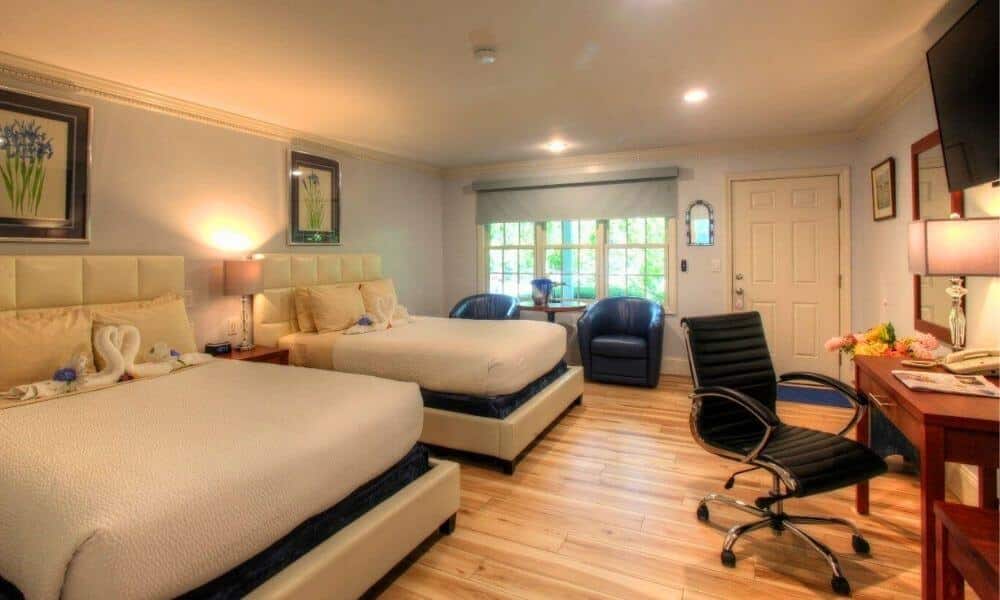 Extra Deluxe room with two queen beds, a work desk, and garden views at Pleasant Bay Village Resort in Chatham, Massachusetts.