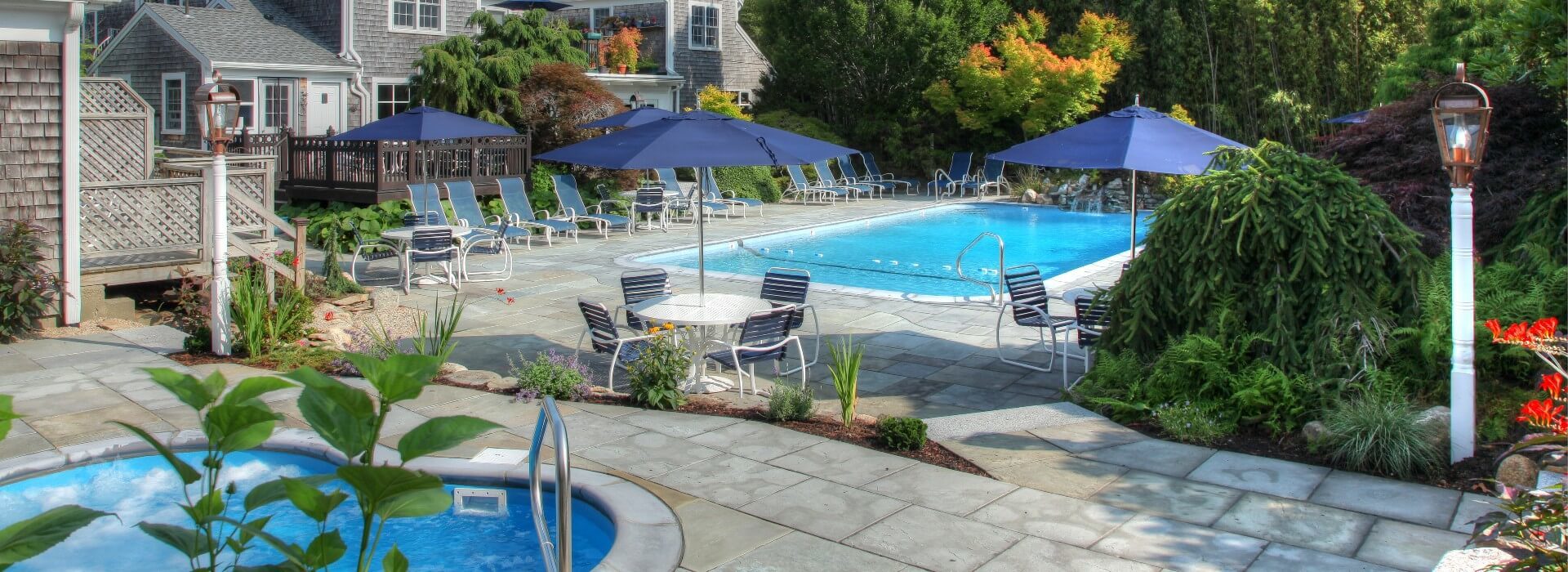 Gorgeous outdoor patio with a large pool surrounded by lounging chairs and a hot tub