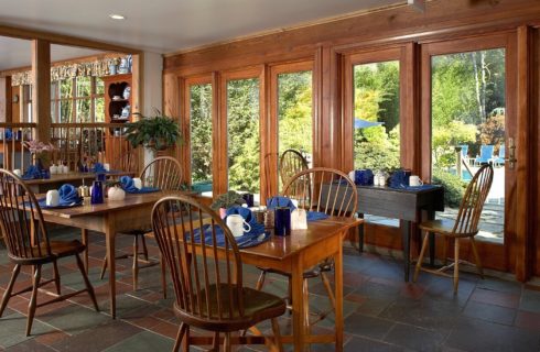 Large dining room with a wall of windows and four tables for two set for breakfast