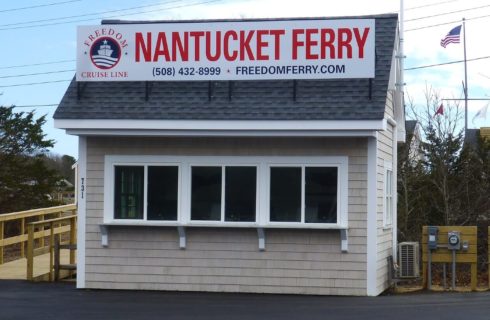 Small beige outdoor building for a local ferry next to a wooden walkway