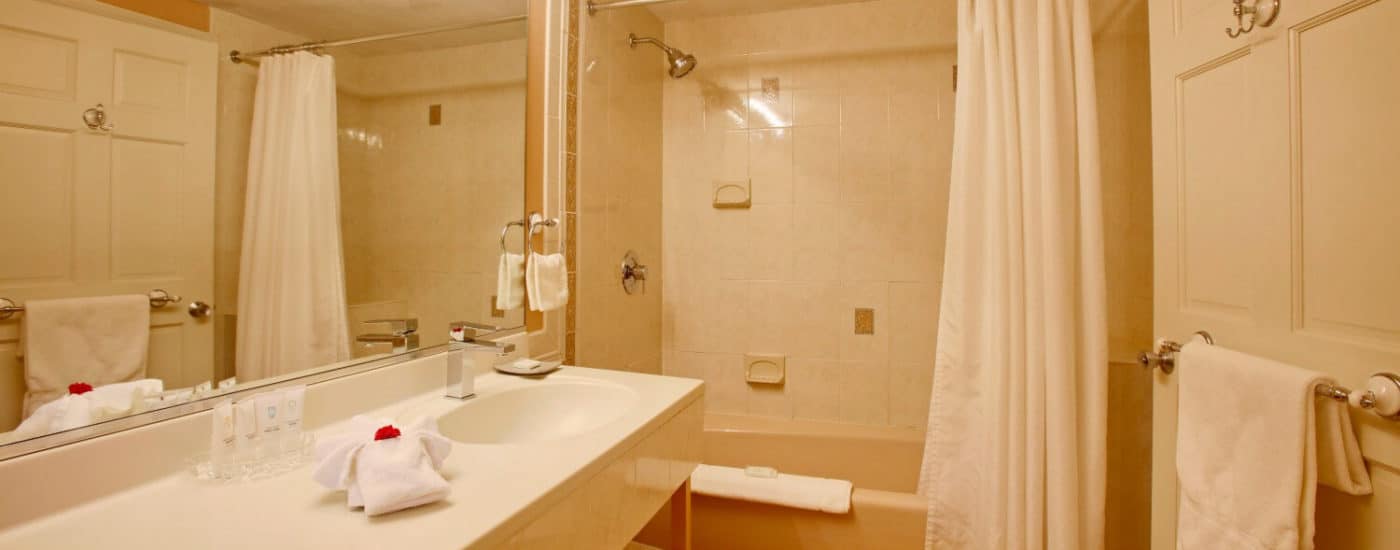 Bathroom with long cream single-sink countertop and bathtub with shower