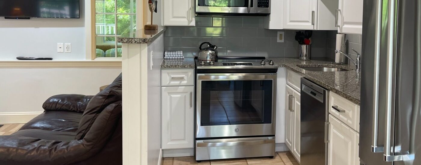 Small kitchen in a cottage with granite countertops, white cabinets and stainless steel appliances