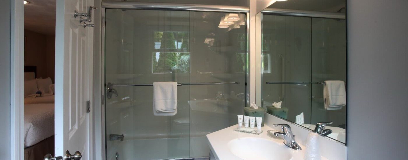 Bathroom with single vanity and large mirror, tub and shower with glass doors